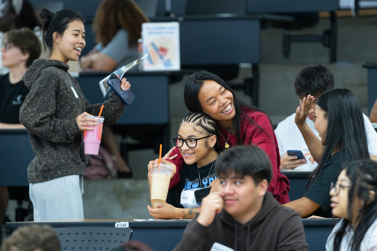 Students in a lecture hall hug and wave at one another at a TLC event.