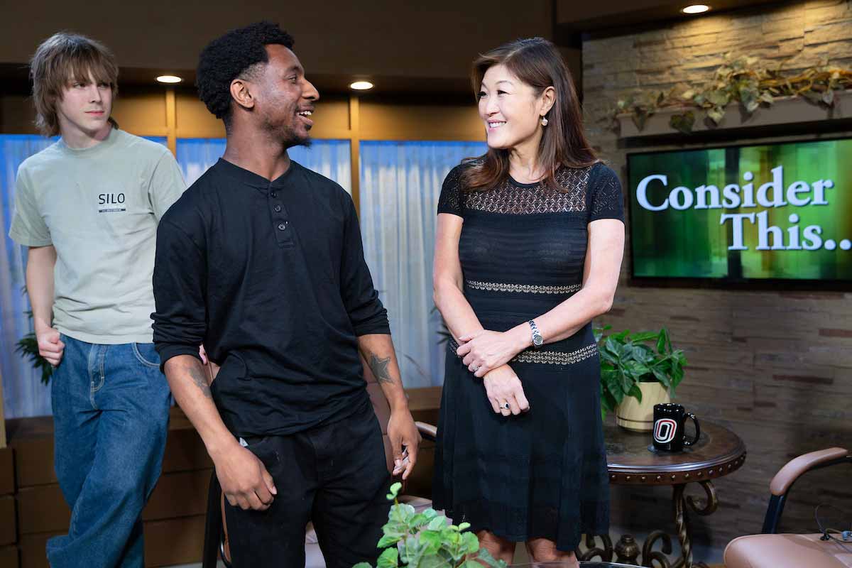 A UNO student stands to the left and faces ABC News’ Juju Chang, while another student stands behind and observes. 