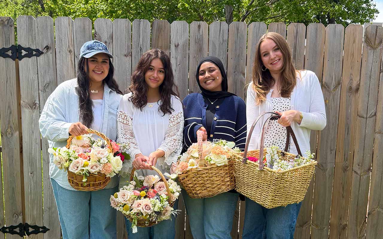 Four individuals stand with baskets full of flowers 