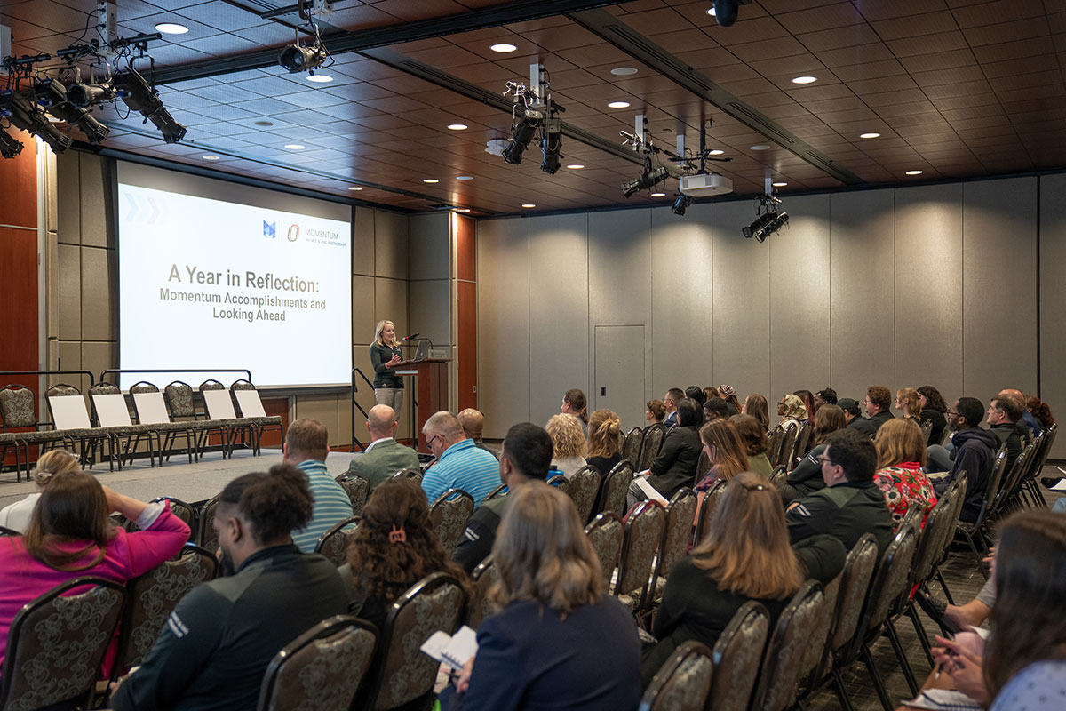 A woman stands at a podium and address an audience.
