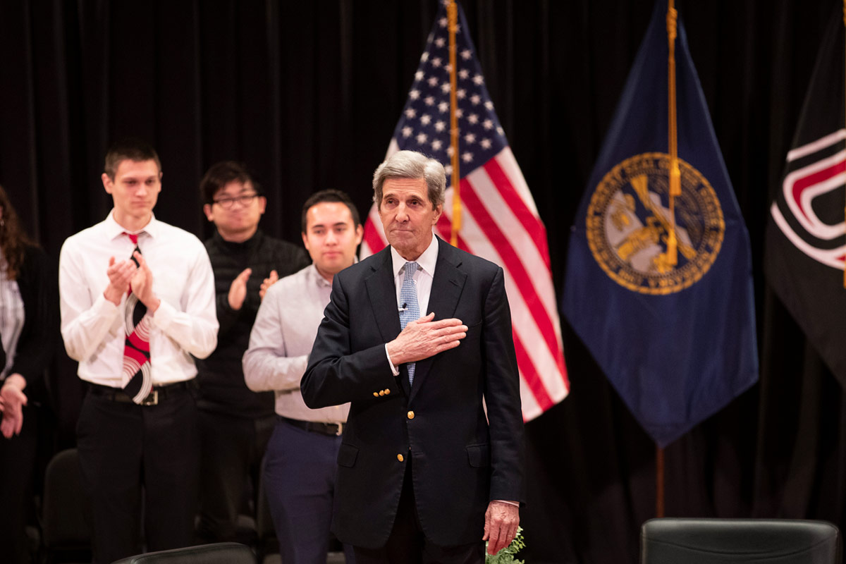 John Kerry holds his hand over his chest on stage at the Hagel Forum in Global Leadership