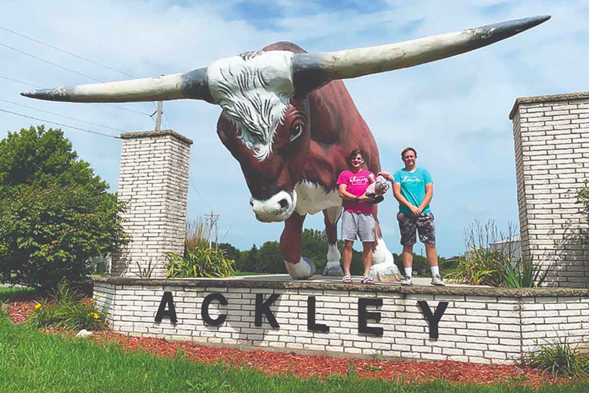 Seth and Austin pose in front of a bull statue.