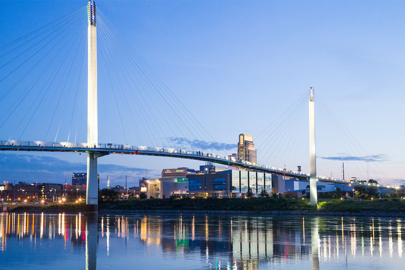 The Bob Kerrey Pedestrian Bridge stretches over the Missouri River in a photo featuring the Omaha skyline.