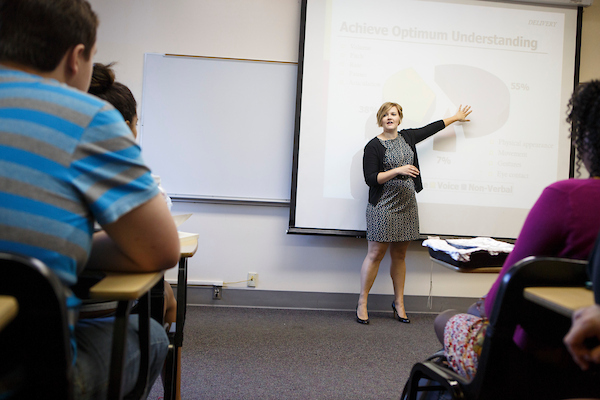 a female teacher stands in front of class