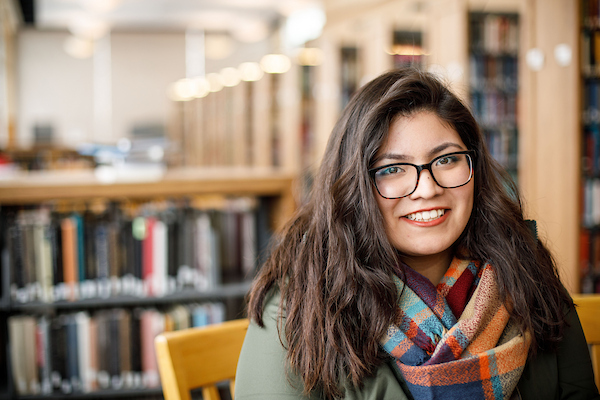 a young smiling latina woman wearing glasses.