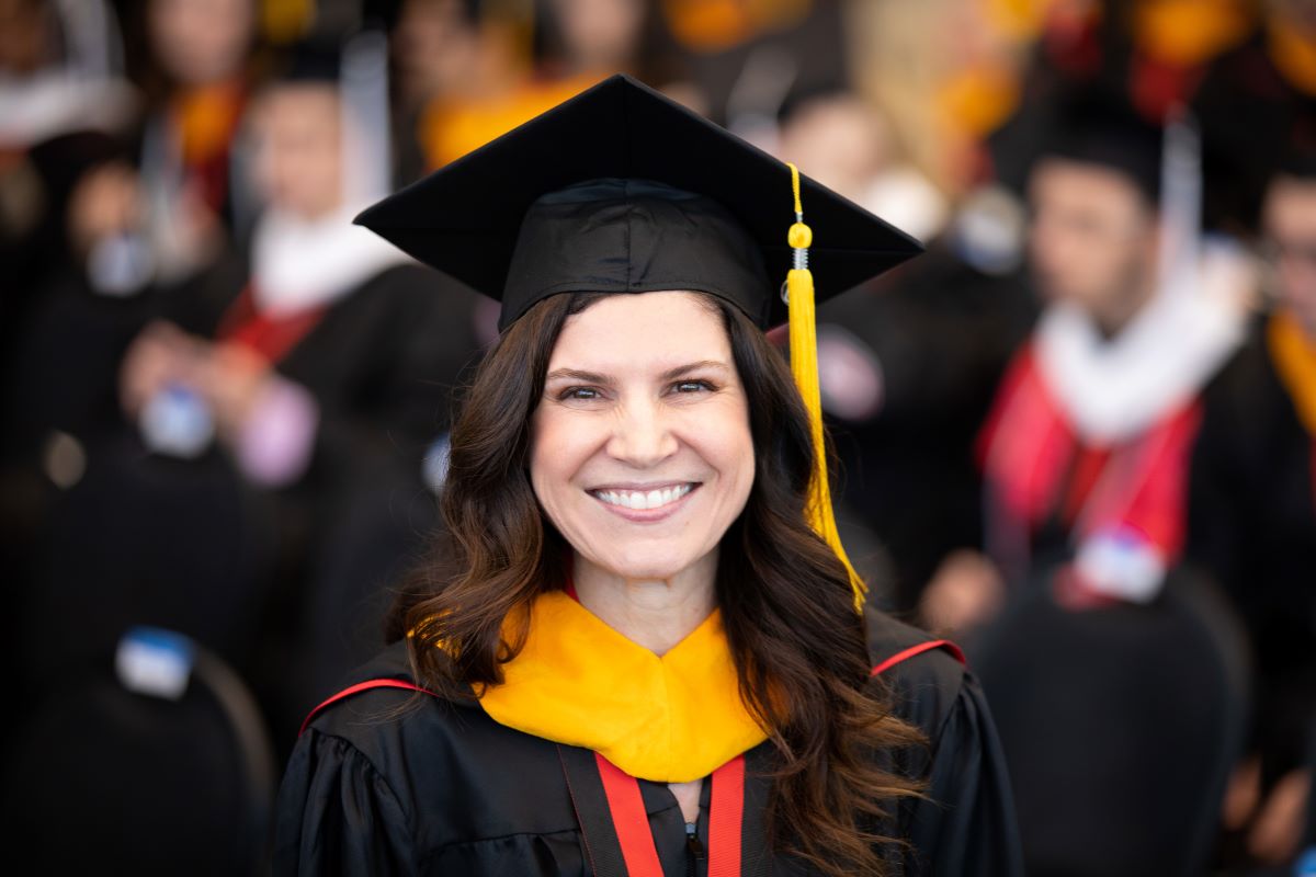 woman smiling wearing commencement cap and gown