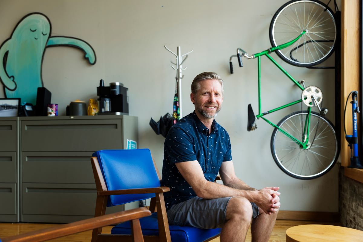 man sitting in chair with bike hanging on wall behind him