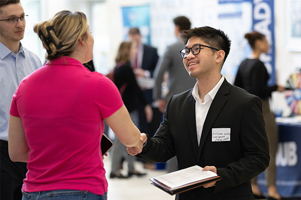 student and recruiter shaking hands at a career fair