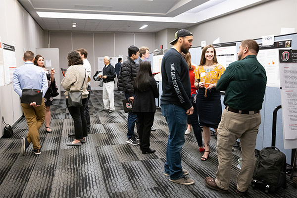 large room filled with research students presenting their research posters to onlookers