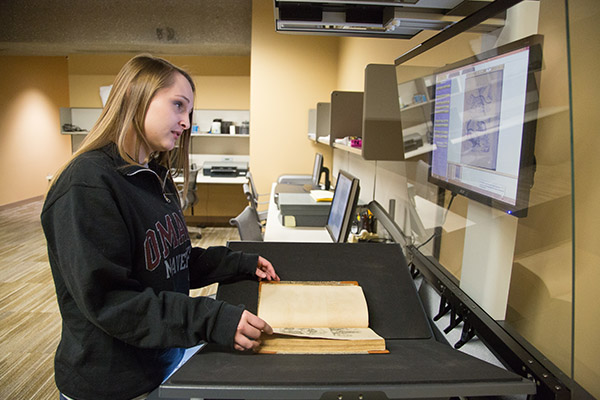 person using a specialized scanner to digitize old looking book