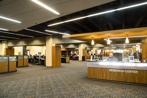wide view of the inside of UNO's Criss library entry space with circulation desk in the background and people standing around