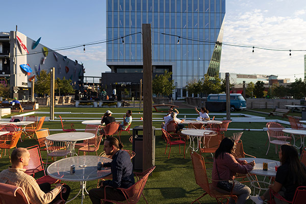 people at outdoor tables in an urban setting at evening