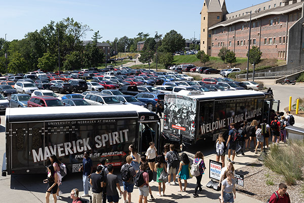large group of students loading into two UNO shuttle buses on campus