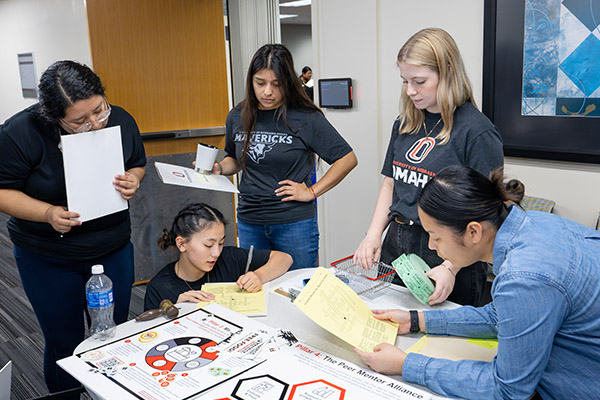 multiple students at a table working on an activity together with colorful materials