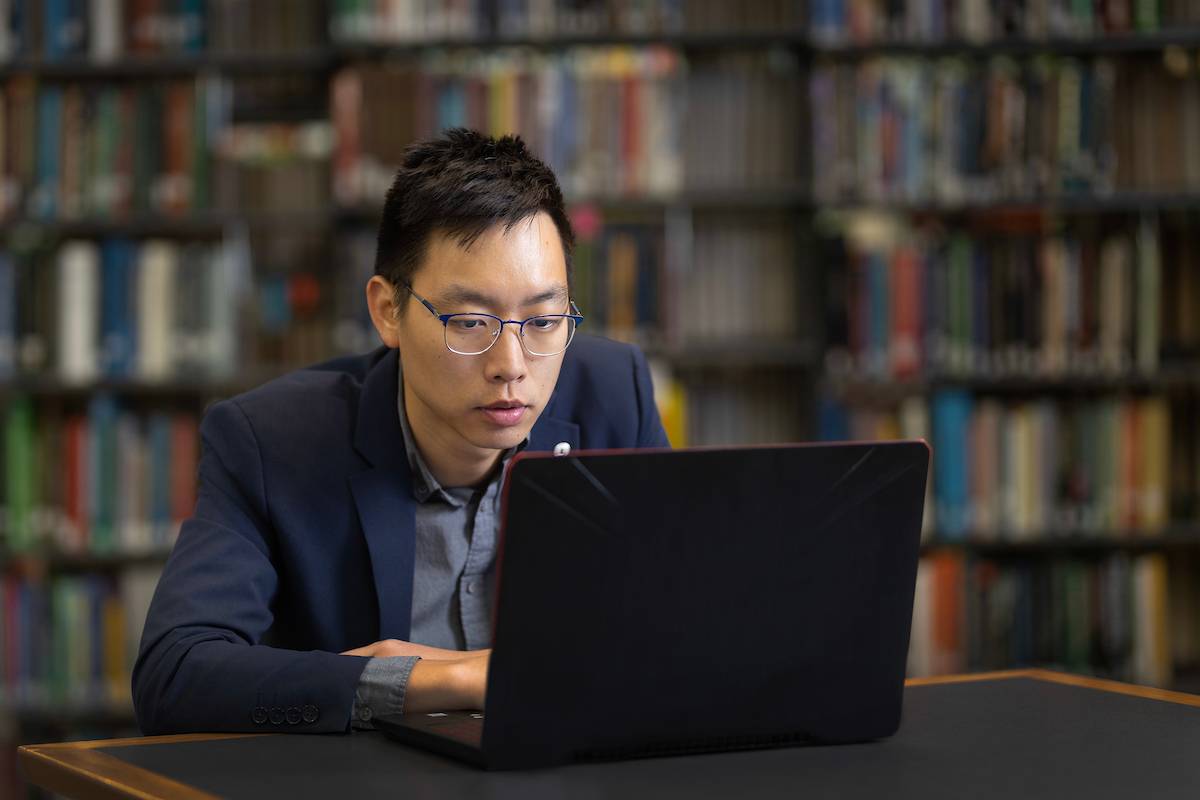 A student works on their laptop in the library.