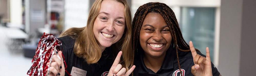 Two female UNO tour guides smiling