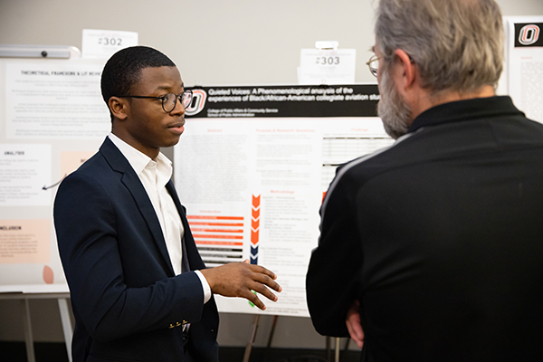 a student discusses his research with a community judge at the rcaf