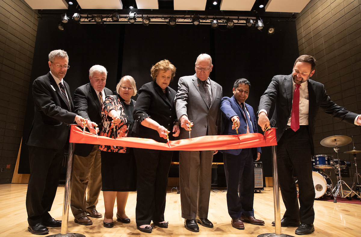 John E. Christensen and others cutting a ribbon at the opening of a concert hall named for him and his wife