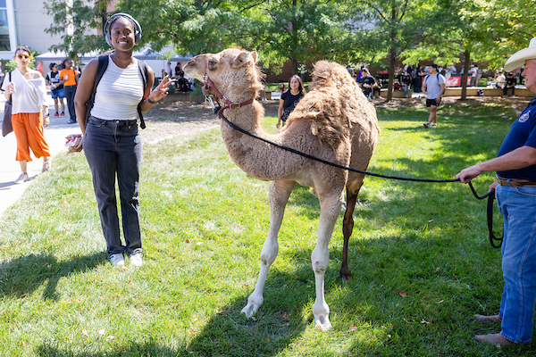 a student poses with a camel on uno's campus