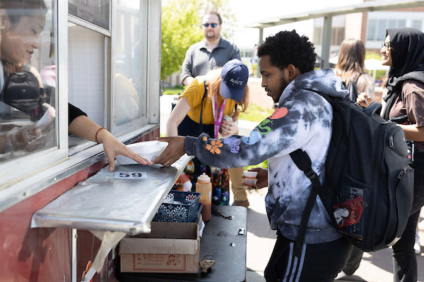 a young man gets his order at the window of a food truck