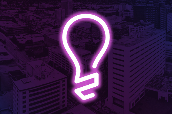 Neon lightbulb icon on a purple city background.