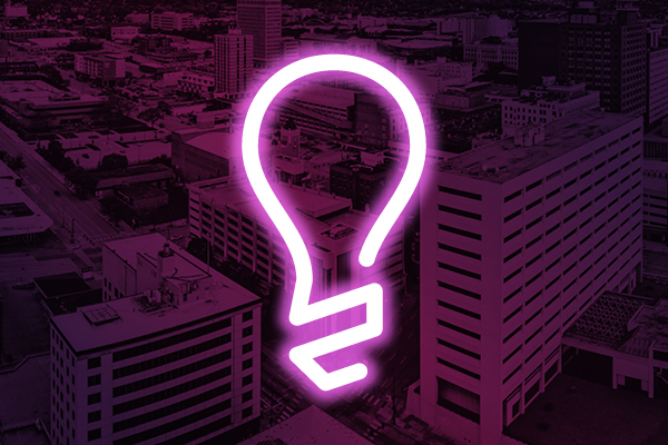 Neon lightbulb icon on a purple city background.