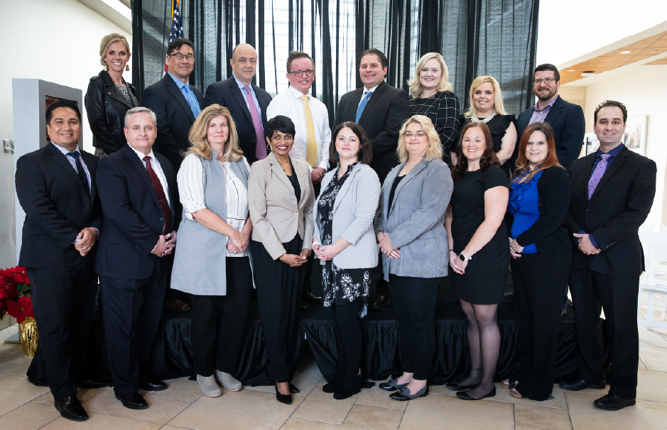 A formal group photo of Executive MBA students and faculty, dressed in business attire, taken at an event or graduation ceremony.
