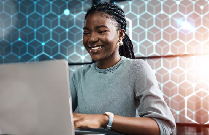 A smiling student works on a laptop with a hexagonal digital background, representing the development of technical and analytical skills in Management Information Systems.
