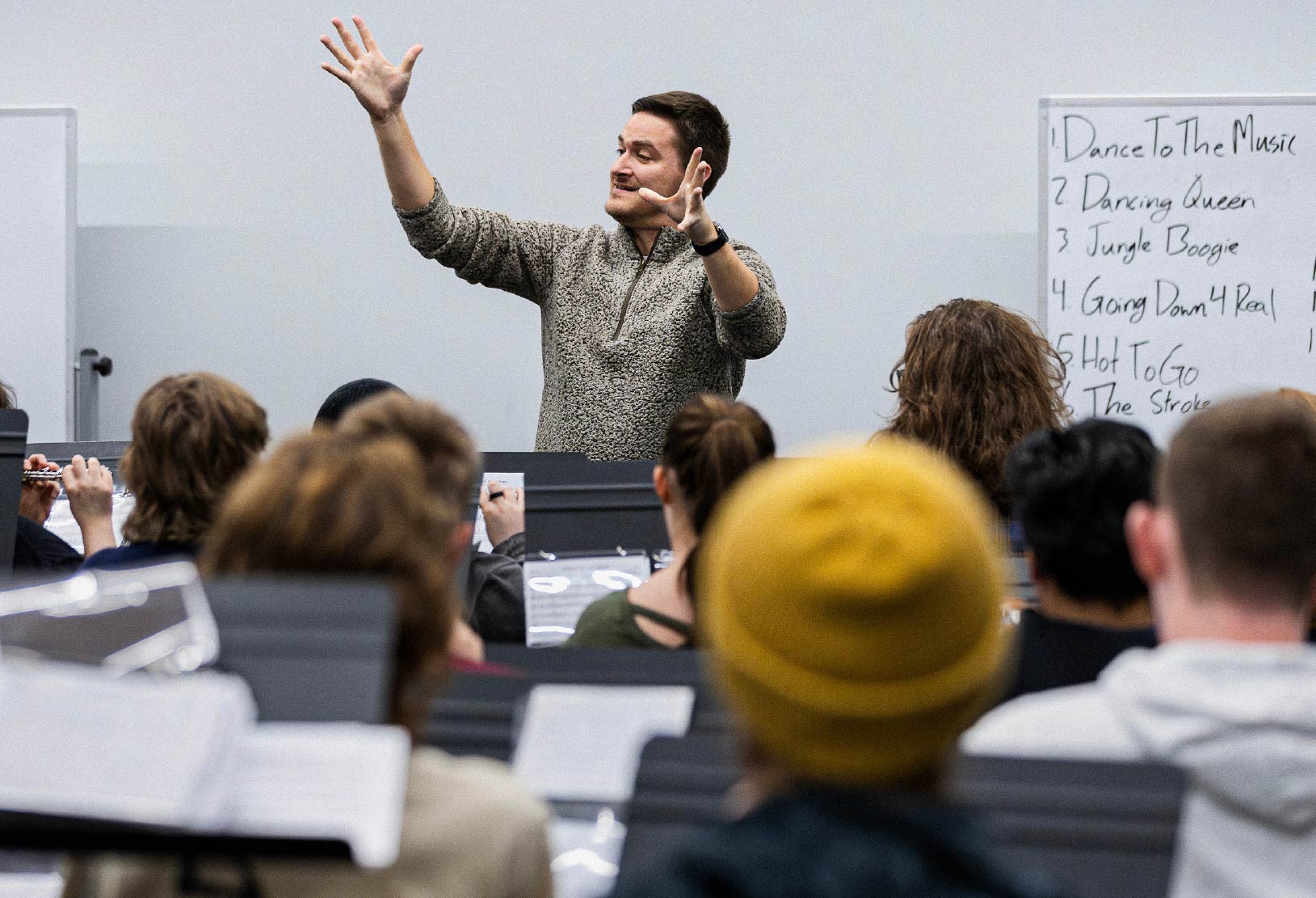 Instructor leading a classroom discussion with students seated in a lecture hall.