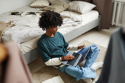 Teenager on floor of bedroom working on laptop