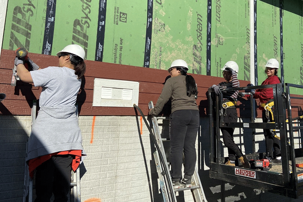 Four students working on a house.