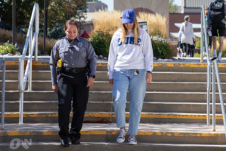 a uno public safety officer and a student walk together on campus