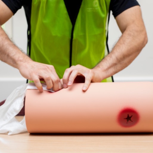 Student packing an open wound from a bullet on a mannequin arm in stop the bleed training class