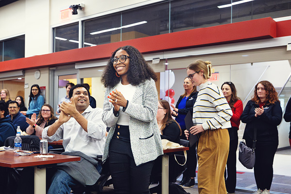 Students gather and talk during a research event inside a large hall.