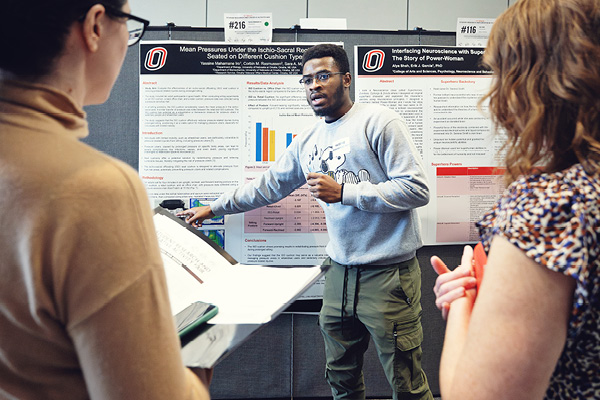 A student presents a poster at a campus research conference.