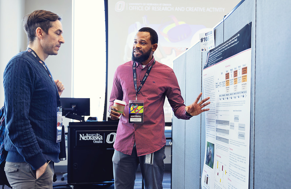 Two students discuss a research poster at the Student Research and Creative Activity Fair.