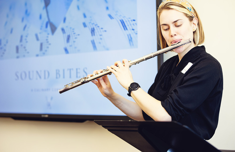 A student plays the flute during a creative performance at the research showcase.