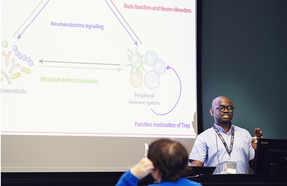 A presenter explains research findings to an audience using a projected slide.