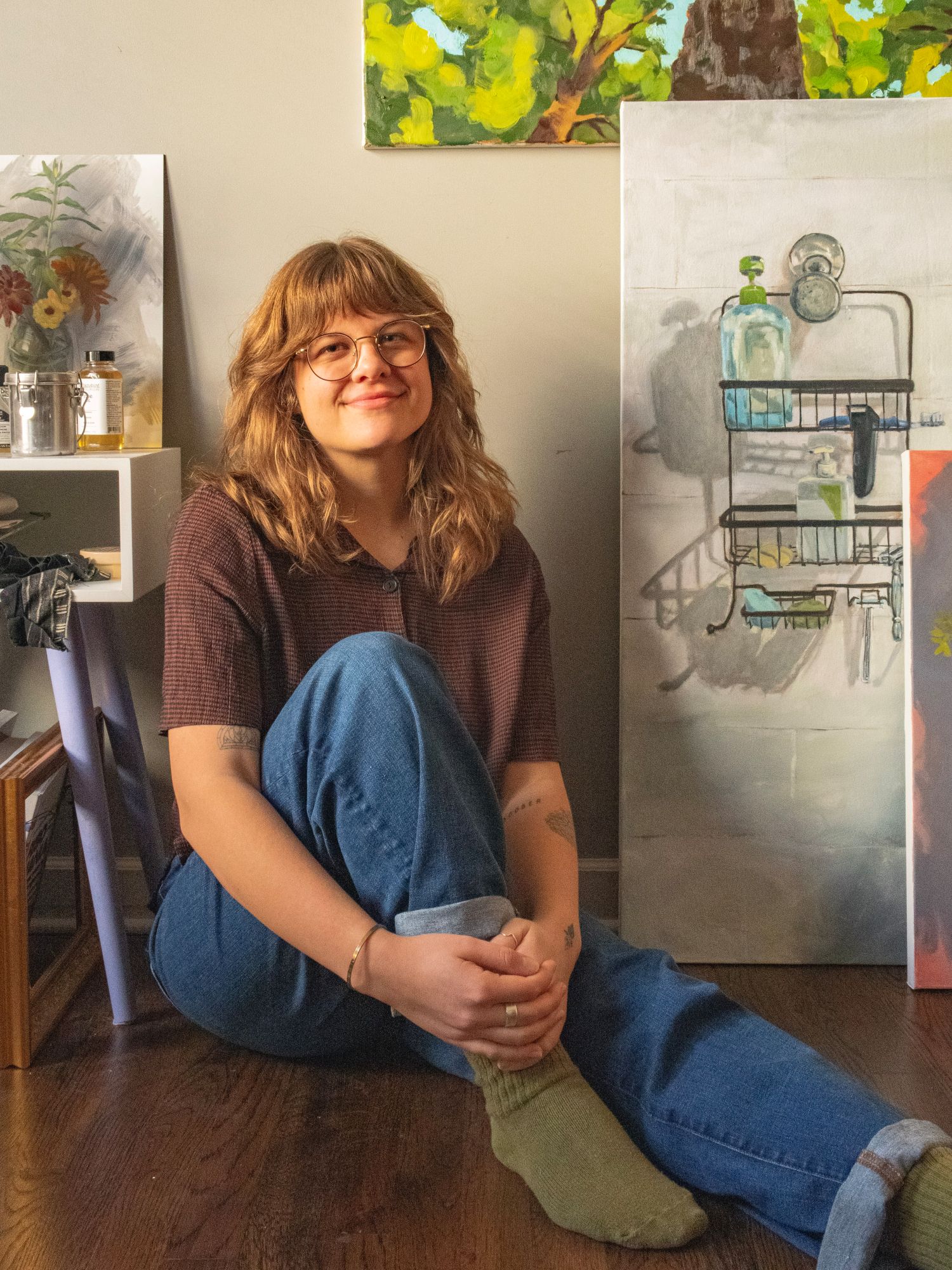 Headshot of Baylee Bennett sitting in her studio, surrounded by her paintings