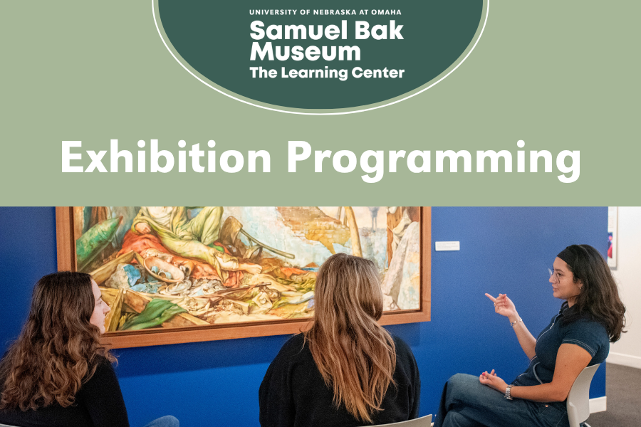 Three students sit in conversation with a painting in front of them.