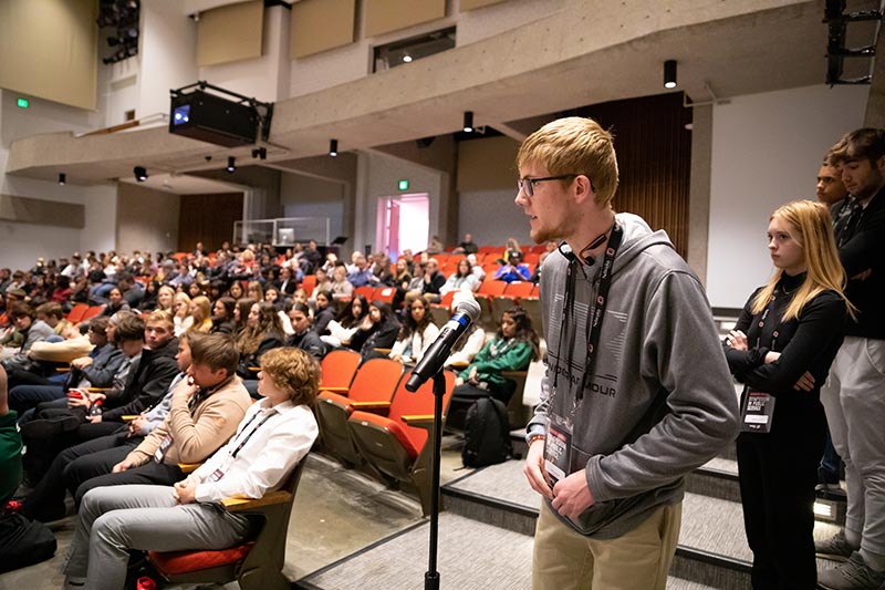 a student stands a ta microphone asking a question.
