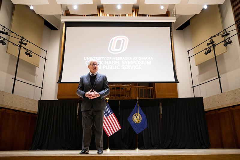 chuck hagel stands on stage speaking to students.