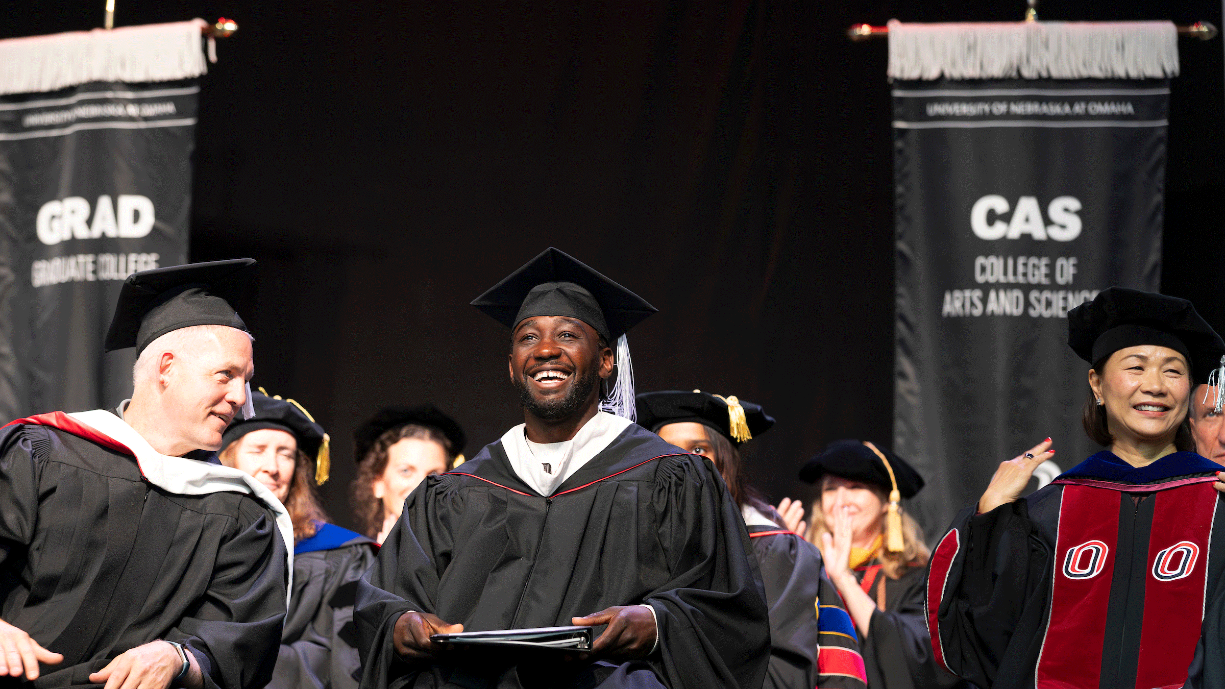 Undefeated world championship boxer Terence “Bud” Crawford smiles as he sits on stage at uno's commencement ceremony - crawford was the ceremony keynote speaker