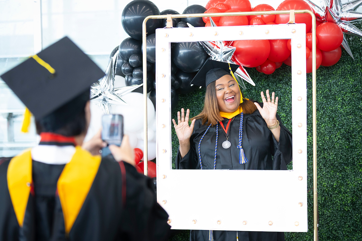 a recent female uno graduate smiles and poses for a picture