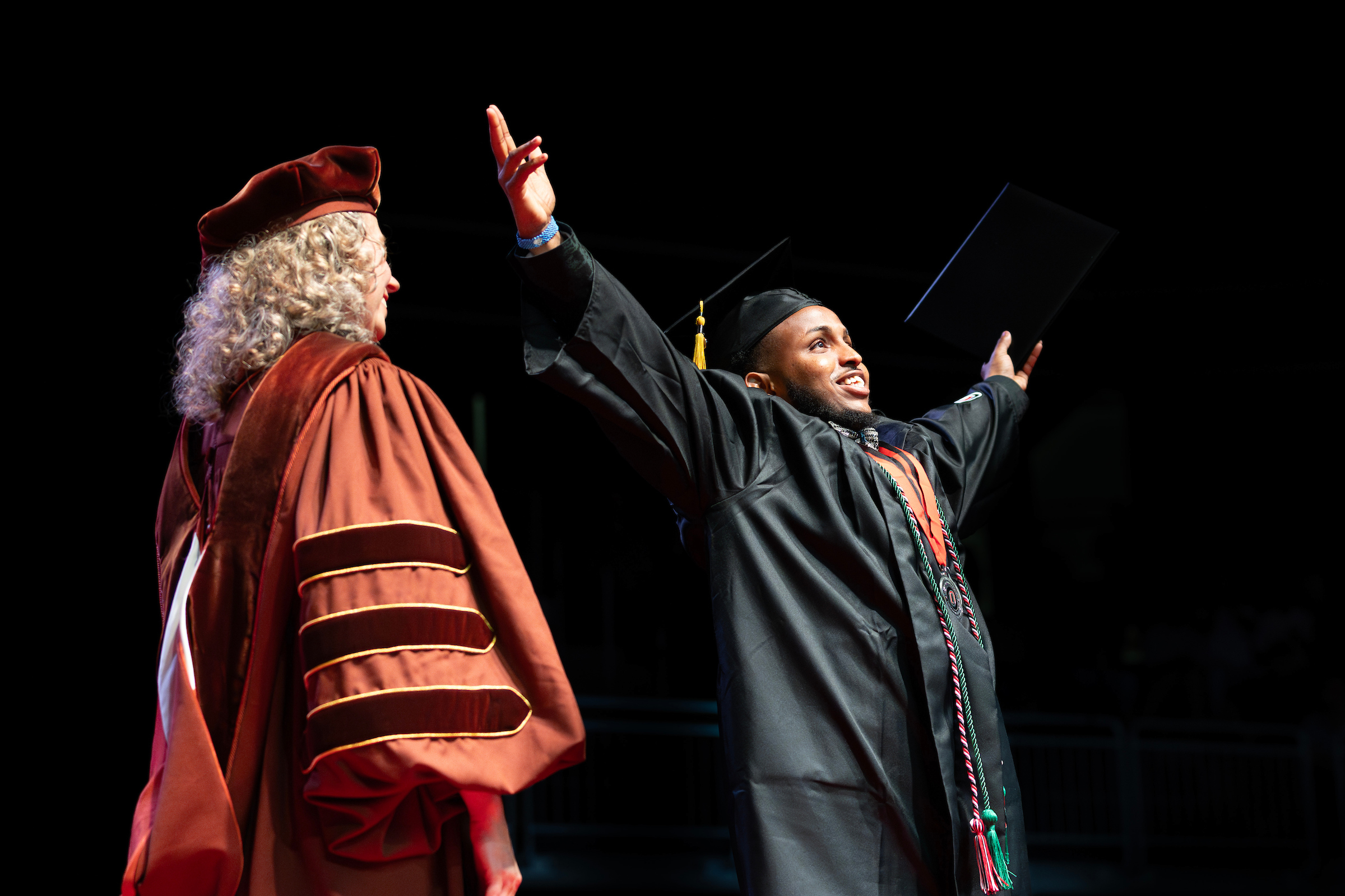 a male student receives his diploma on stage at uno's commencement ceremony