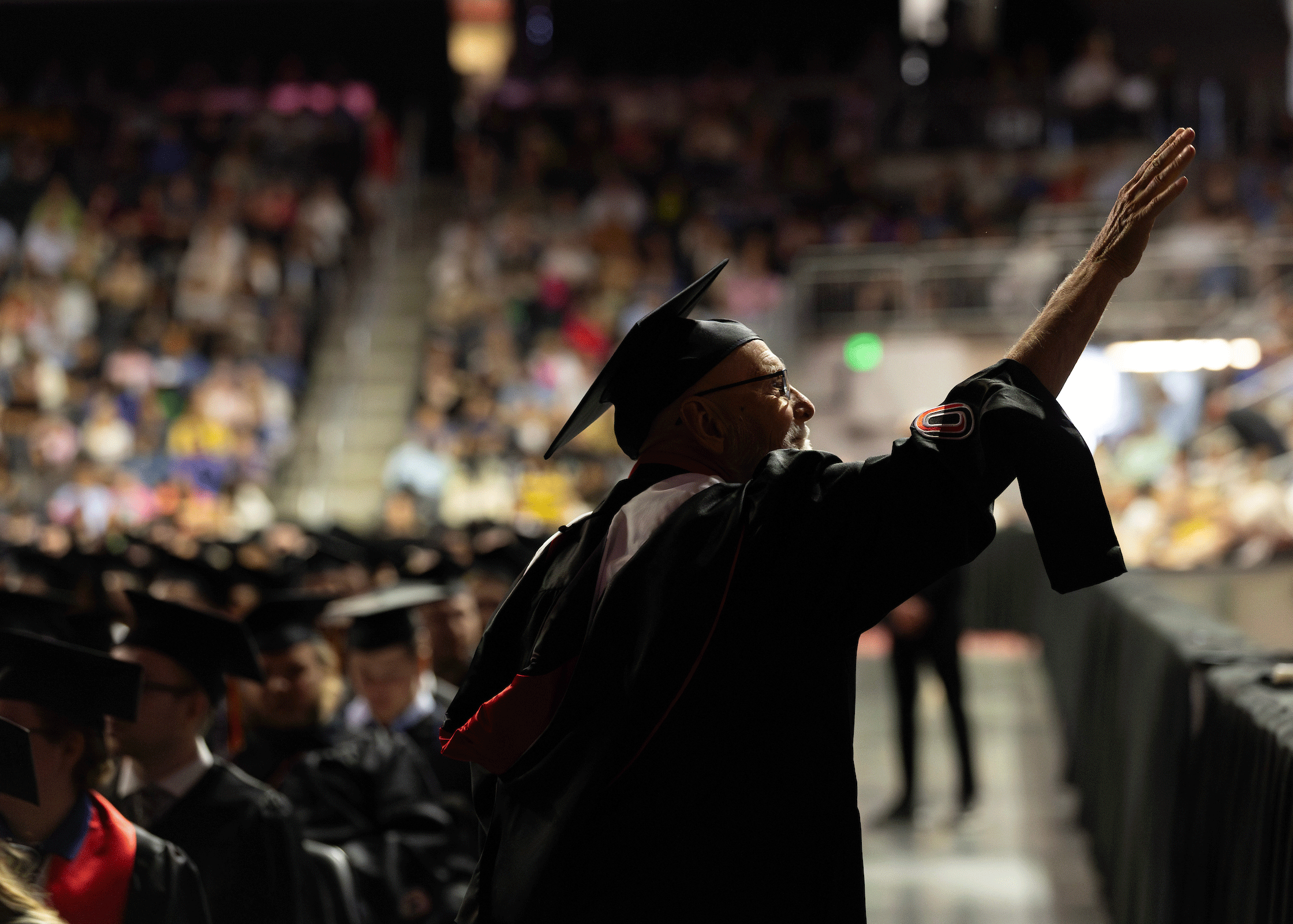 a faculty member reaches out to someone at the commencement ceremony