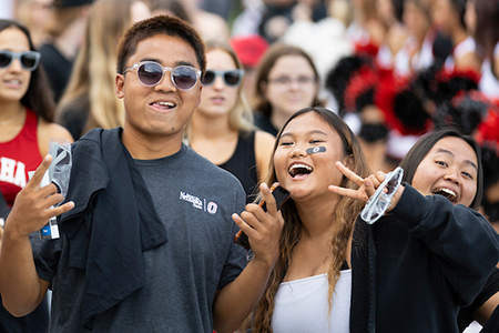 two students dressed in mav gear cheering at a soccer game