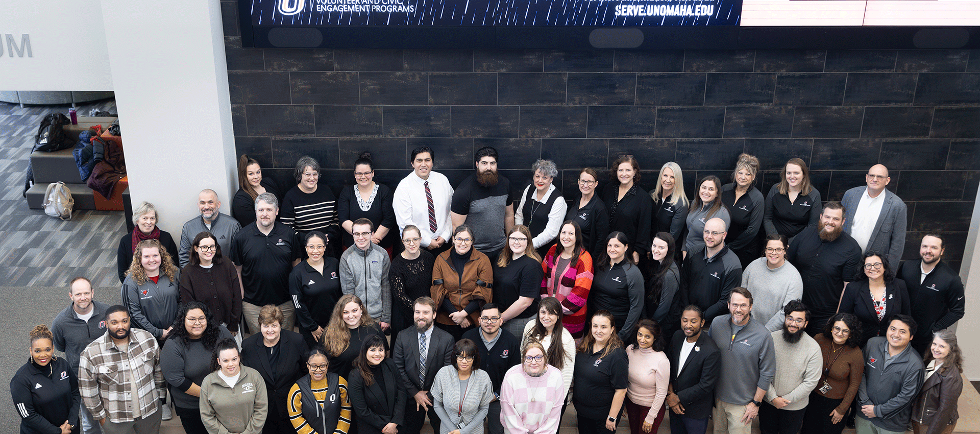 Group photo of the Division of Student Life and Wellbeing professional staff gathered indoors, arranged in several rows and smiling at the camera.