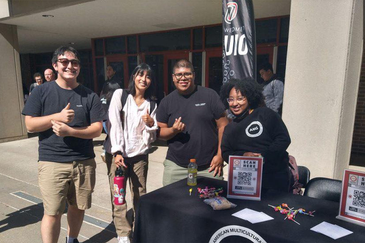 Students in the American Multicultural Students Agency table outside of the student center.