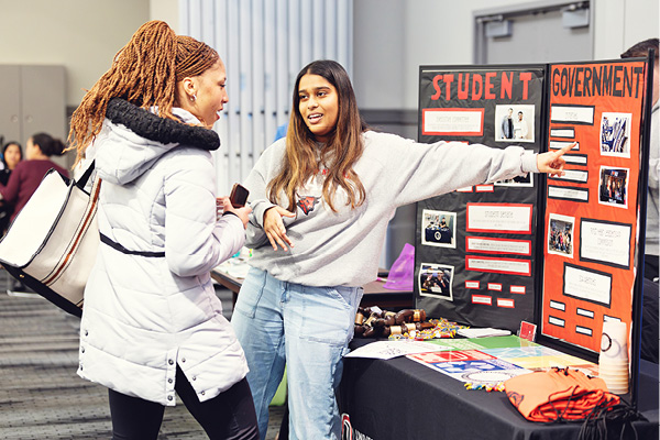 Students talking near a display board for a student organization.